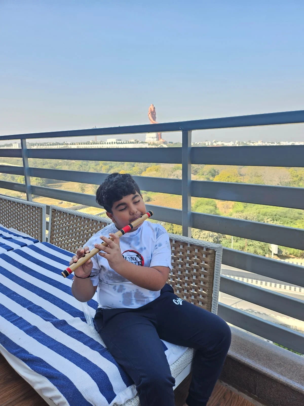 Hridan exploring music on a flute while sitting on a balcony