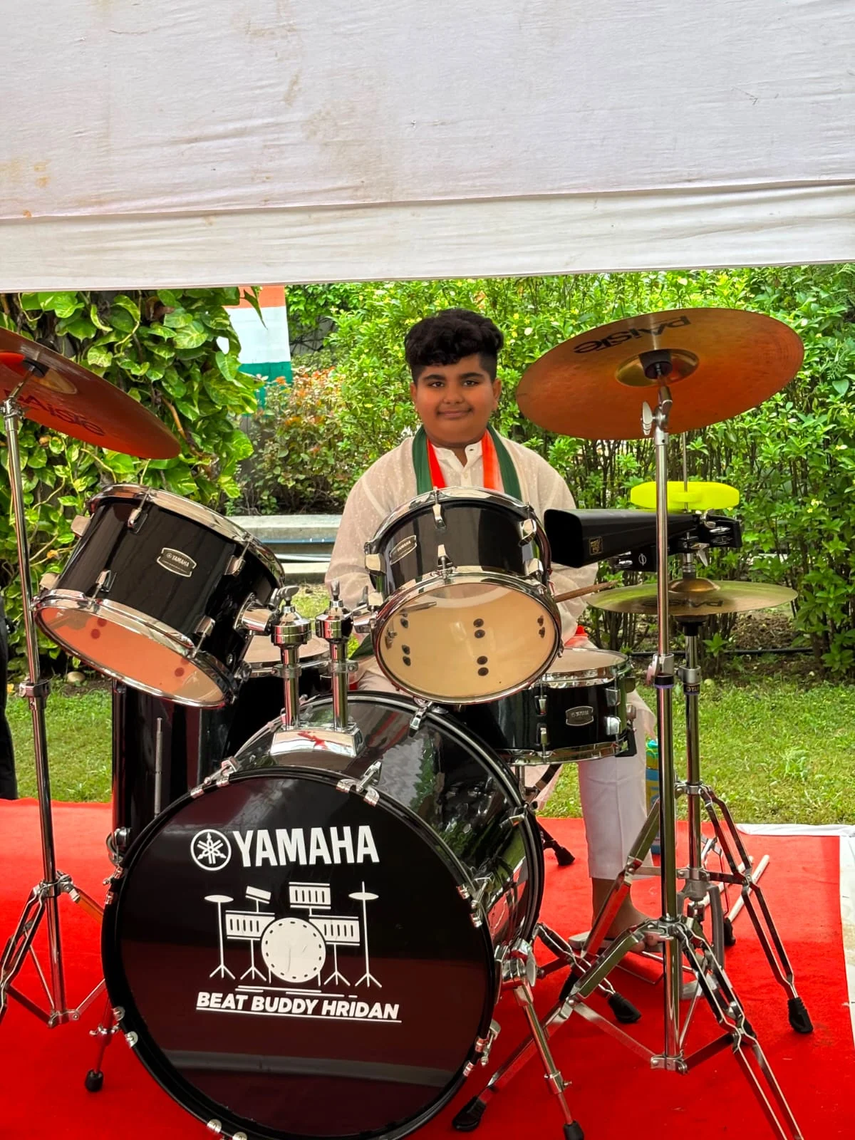 Hridan playing an acoustic drum kit at an outdoor event