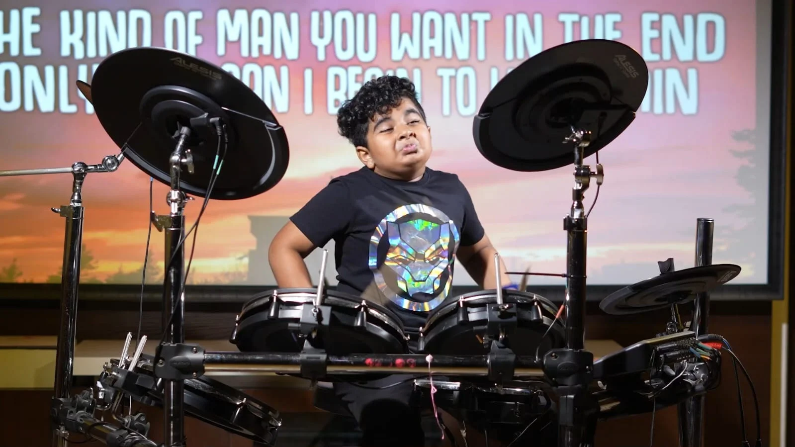 Hridan playing on stage, with colourful lights behind the drums